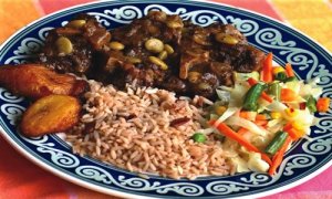 Jamaican Oxtail dish served with vegetables, plantains and rice and peas